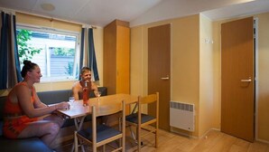 Una habitació amb un sofà, una taula, cadires, una finestra i una porta.