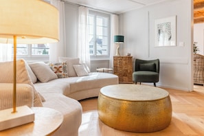 Una sala de estar moderna con un sofá, un reposapiés redondo y una lámpara.