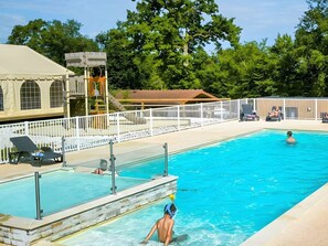A swimming pool with a lifeguard tower, lounge chairs, and a fenced deck area. - Mobile home with AC - 4 guests (Arrigny)