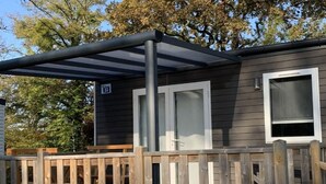 Une petite cabane avec une terrasse, une porte et une fenêtre.