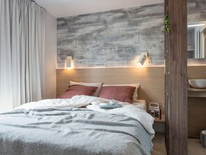 Ein modernes Schlafzimmer mit Bett, Nachttisch und einer Wandleuchte.