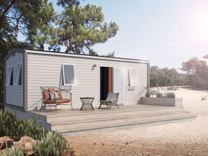 A small, single-story cabin with a porch, two chairs, and a bench. - Cozy mobile home - 6 guests (Puy-l'Évêque)