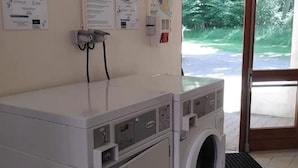 Een wasruimte met een voorlader wasmachine, een droger en een wandbevestigde papieren dispenser.
