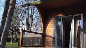 Een houten chalet met een veranda, een schuifpui en een omheind gebied.
