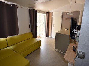 A modern room with a yellow sofa, a television, and a desk with a computer. - Mobile home - AC - 2 guests (Méolans-Revel)