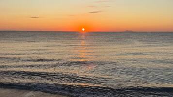 Un coucher de soleil sur une mer calme aux vagues douces.