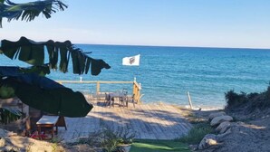 Ein Strand mit einer Holzterrasse, einer Flagge und Blick auf den Ozean.