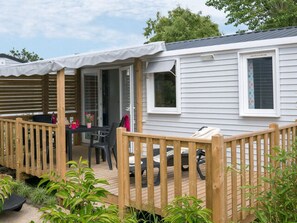 A mobile home with a wooden deck, a covered porch, and a small garden area. - Comfortable mobile home - 6 guests (Saint-Georges-d'Oléron)