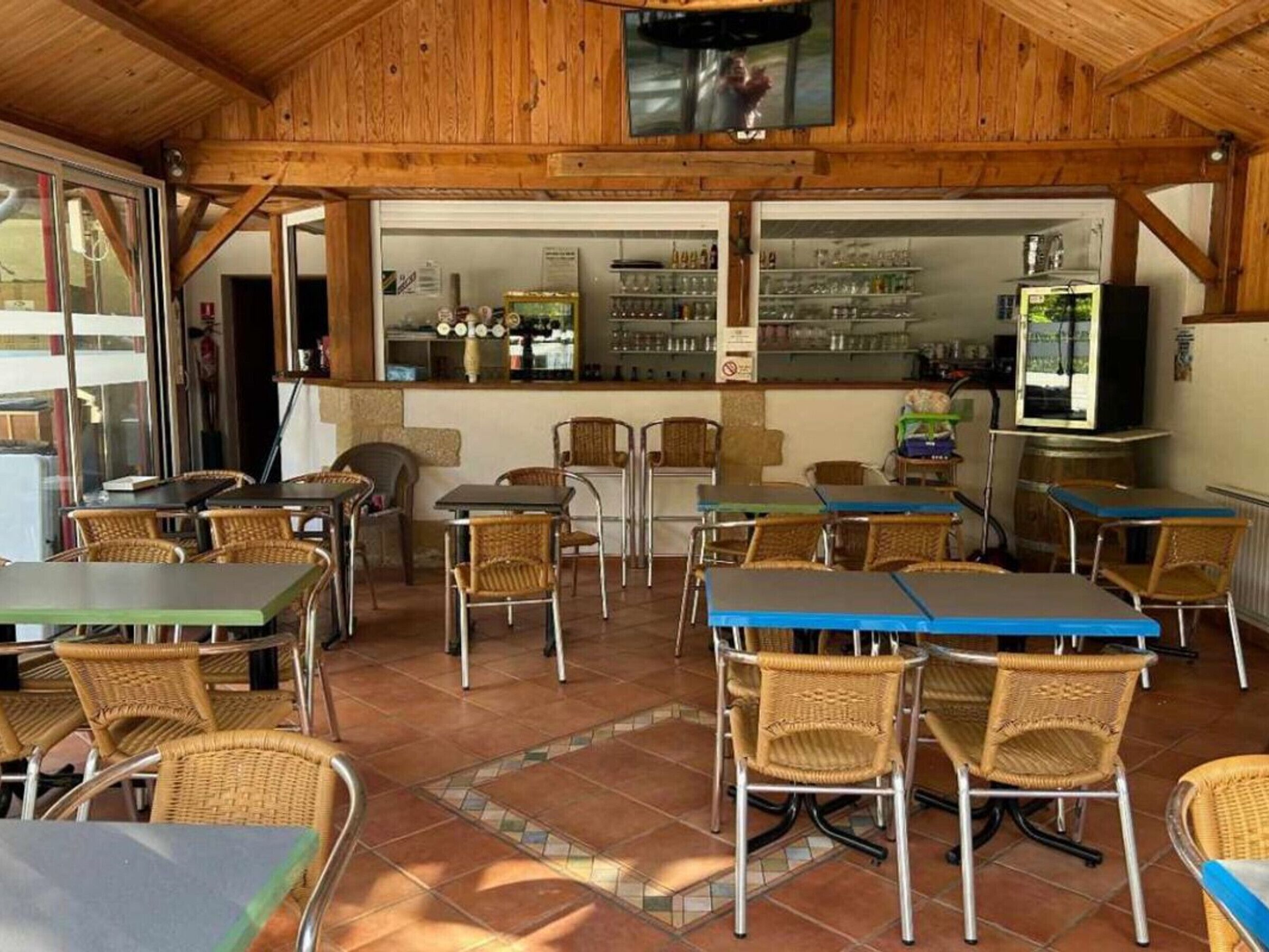 A restaurant with wooden interior, tiled floor, and wicker chairs. Tables are arranged for dining.