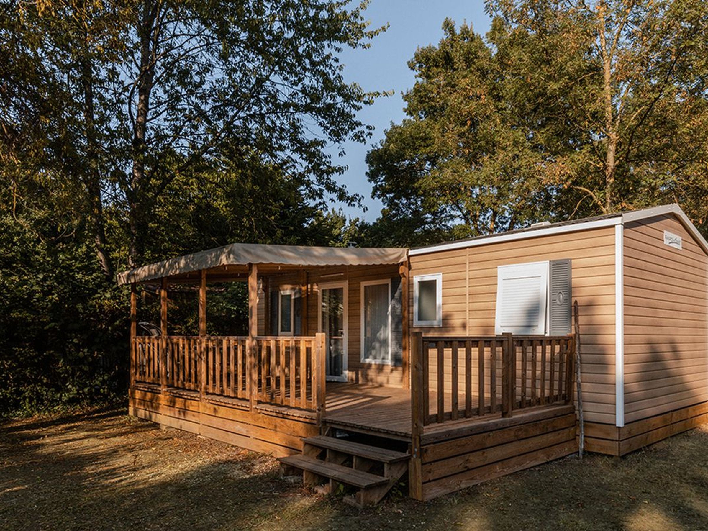 Une cabane en bois avec un porche, une terrasse couverte et une petite fenêtre.