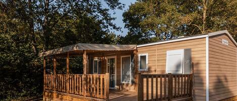 A wooden cabin with a porch, a covered deck, and a small window.