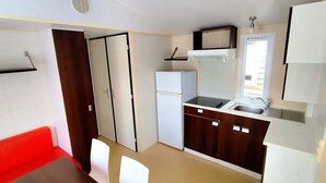 A compact kitchen with a refrigerator, stove, microwave, and sink. - Mobile home, pets allowed - 4 guests (Sauxillanges)