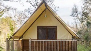 En liten, envåningsbyggnad med ett triangulärt tak, en träveranda med trappsteg och ett fönster med gardiner.