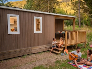 Eine Holzhütte mit zwei Fenstern, einer Veranda und einer Terrasse.
