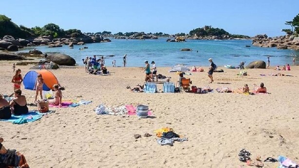 Una playa con gente, tiendas de campaña y un cielo despejado.