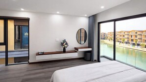 Une chambre d’hôtel moderne avec un grand lit, une table de chevet agrémentée d’un vase, un miroir et une vue sur une piscine et des immeubles.