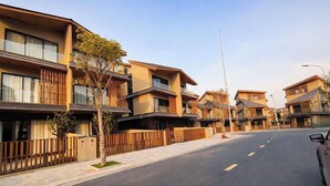 Une rue résidentielle bordée de maisons modernes, un ciel dégagé et une voiture garée.