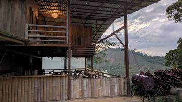 A rustic wooden building with a balcony, outdoor seating, and a barbecue grill.