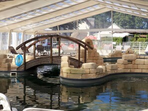 An indoor swimming pool with a wooden bridge, lounge chairs, and a covered area with a view of the outside. - Cozy mobile home, dog welcome - 4 guests (Luynes)
