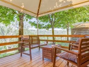 A wooden deck with a covered seating area, a table, and chairs.