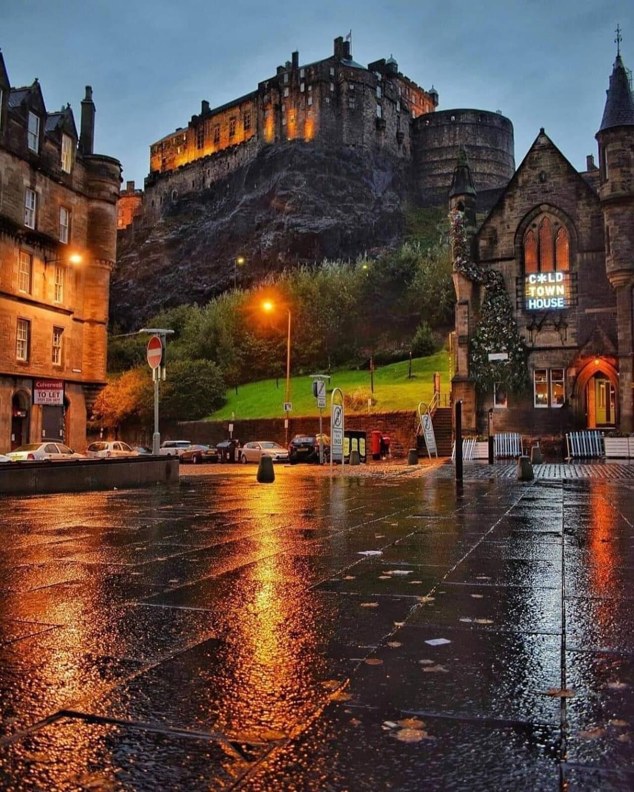A castle on a hill with a lit street in the foreground.