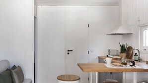 Une cuisine de taille réduite avec une table en bois, des tabourets, un four à micro-ondes et une plante en pot.