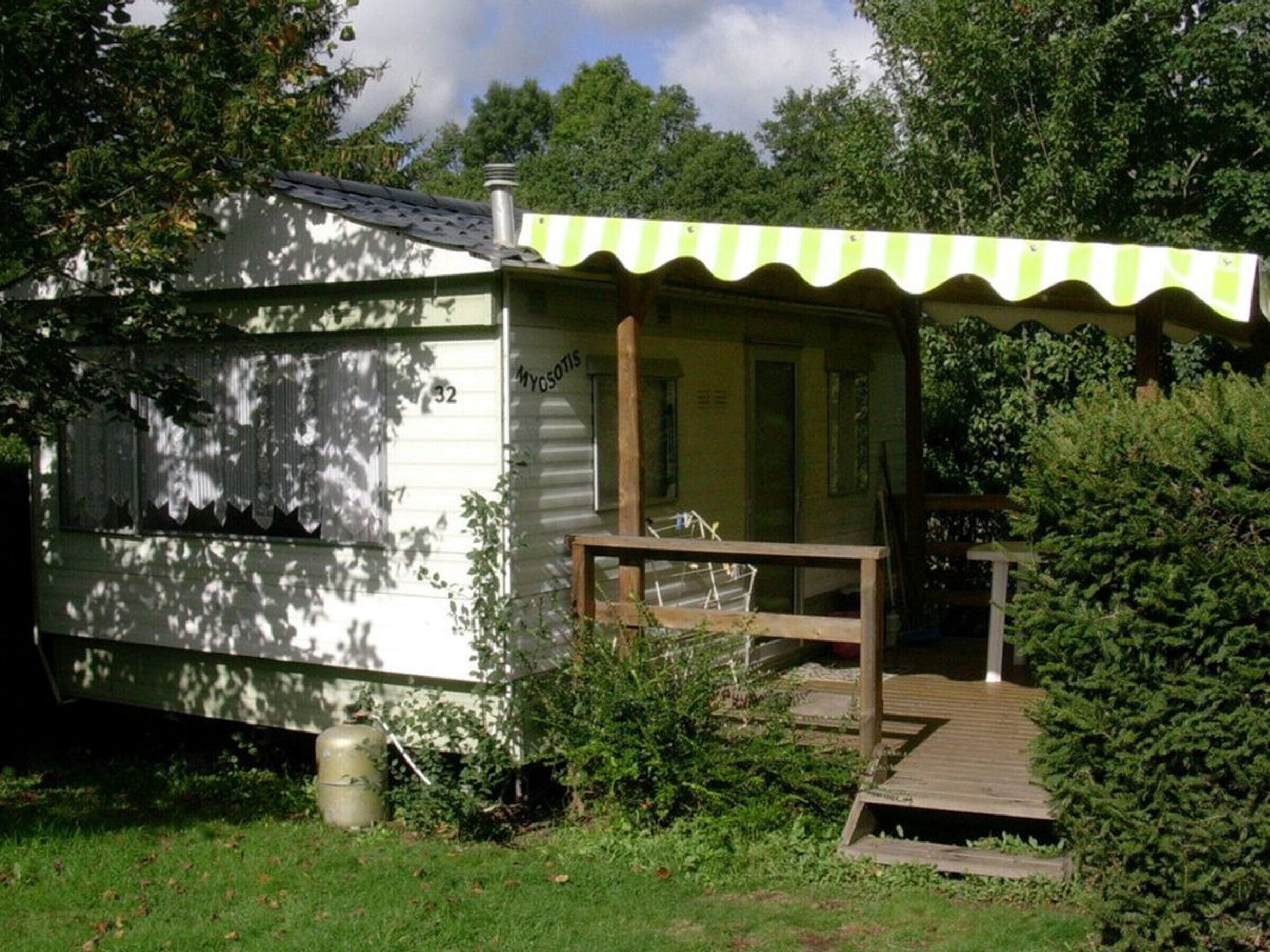 Une petite cabane à un seul étage, dotée d’un porche, d’une cheminée et d’un espace extérieur couvert aménagé en coin salon.