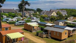 A campsite with mobile homes, a covered deck with chairs, and a dirt path. - Cozy mobile home - 2 guests (Perros-Guirec)