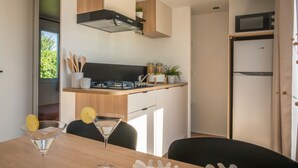 A modern kitchen with a built-in stove, microwave, and a small island with a sink. - Mobile home, pets welcome - 5 guests (La Châtre)