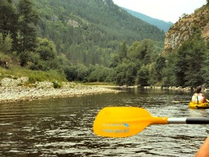 Ein Fluss mit einem Kajak und einem Paddel im Vordergrund.