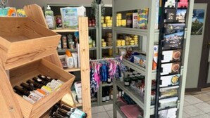 A retail display with shelves stocked with various products, a wooden crate with bottles, and a rack with promotional materials. - Mobile home with air conditioning - 4 guests (Monplaisant)