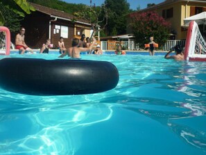 A swimming pool with clear water, a black floating object, and people in the background. - Mobile home with air conditioning - 4 guests (Monplaisant)