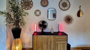 Una habitación con un armario de madera, una planta en maceta y relojes en la pared.