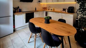 Una cocina moderna con armarios blancos, una mesa de comedor de madera y sillas negras.
