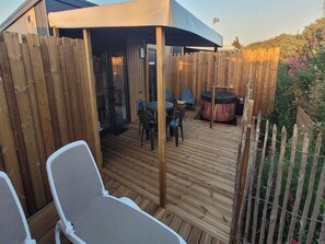 Une terrasse en bois avec des sièges d’extérieur, un jacuzzi et un espace abrité.