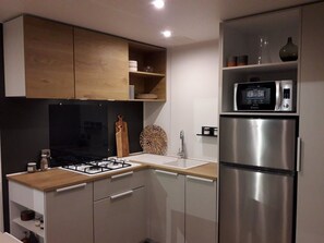 A modern kitchen with a gas stove, stainless steel refrigerator, and a microwave. - Mobile home with air conditioning - 4 guests (Vans)