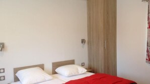 A bedroom with a bed, a wardrobe, and a wall-mounted light fixture. - Mobile home AC, pets welcome - 4 guests (Lézignan-Corbières)