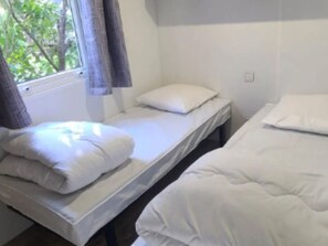Ein Zimmer mit zwei Einzelbetten, jeweils mit Kissen und Decke.