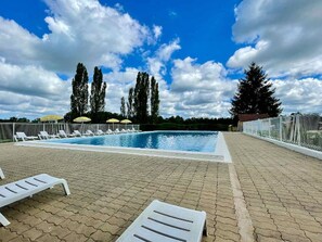 A swimming pool with lounge chairs and umbrellas, surrounded by trees and a clear sky. - Mobil-home - pets welcome - 6 guests (La Douze)