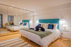 A modern bedroom with a large mirror, a bed with a teal headboard, and a plush toy on the bed. - Exceptional Villa a/c 4br/8p With Pool & Sea View (Grimaud)