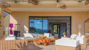 Eine moderne Lounge-Bereich im Freien mit Korbmöbeln, einer Couch und einem Couchtisch.