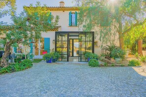 A building with a glass entrance, outdoor seating, and potted plants. - Exceptional Villa a/c 4br/8p With Pool & Sea View (Grimaud)