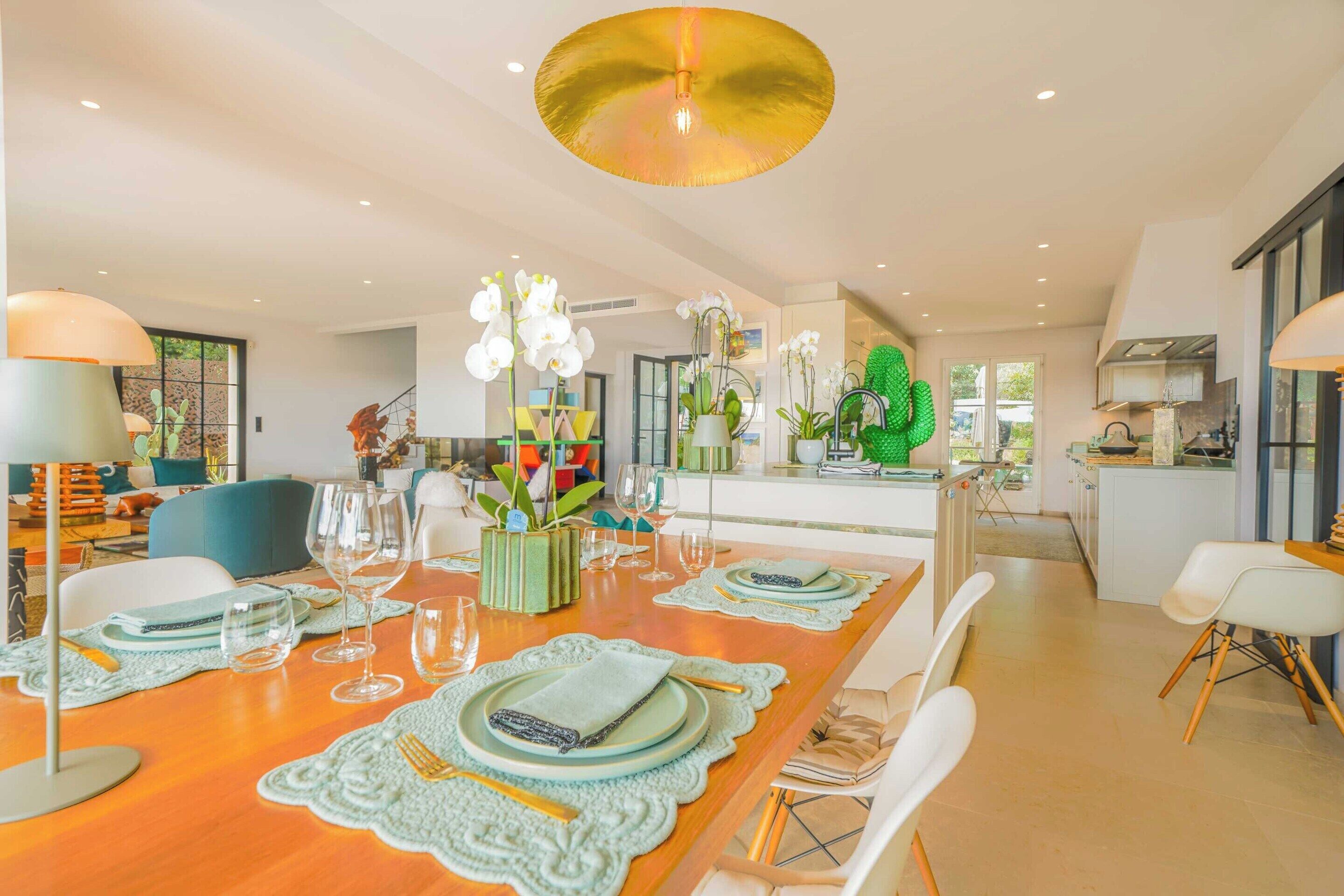 A modern dining area with a wooden table set for a meal, surrounded by white chairs.