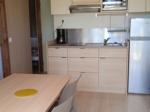A compact kitchen with a sink, stove, and a refrigerator. - Chalet - 5 guests, pets welcome (Pleaux)