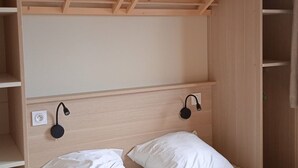 A bedroom with a wooden bunk bed, two bedside lamps, and a power outlet.