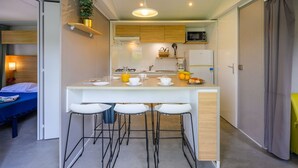 A compact kitchen with a central island, bar stools, and a microwave. - Mobile home, pets welcome - 5 guests (Saint-Jean-de-Monts)