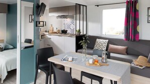A compact living space with a kitchenette, dining area, and a sofa with a view. - Mobile home, pets welcome - 5 guests (Saint-Jean-de-Monts)