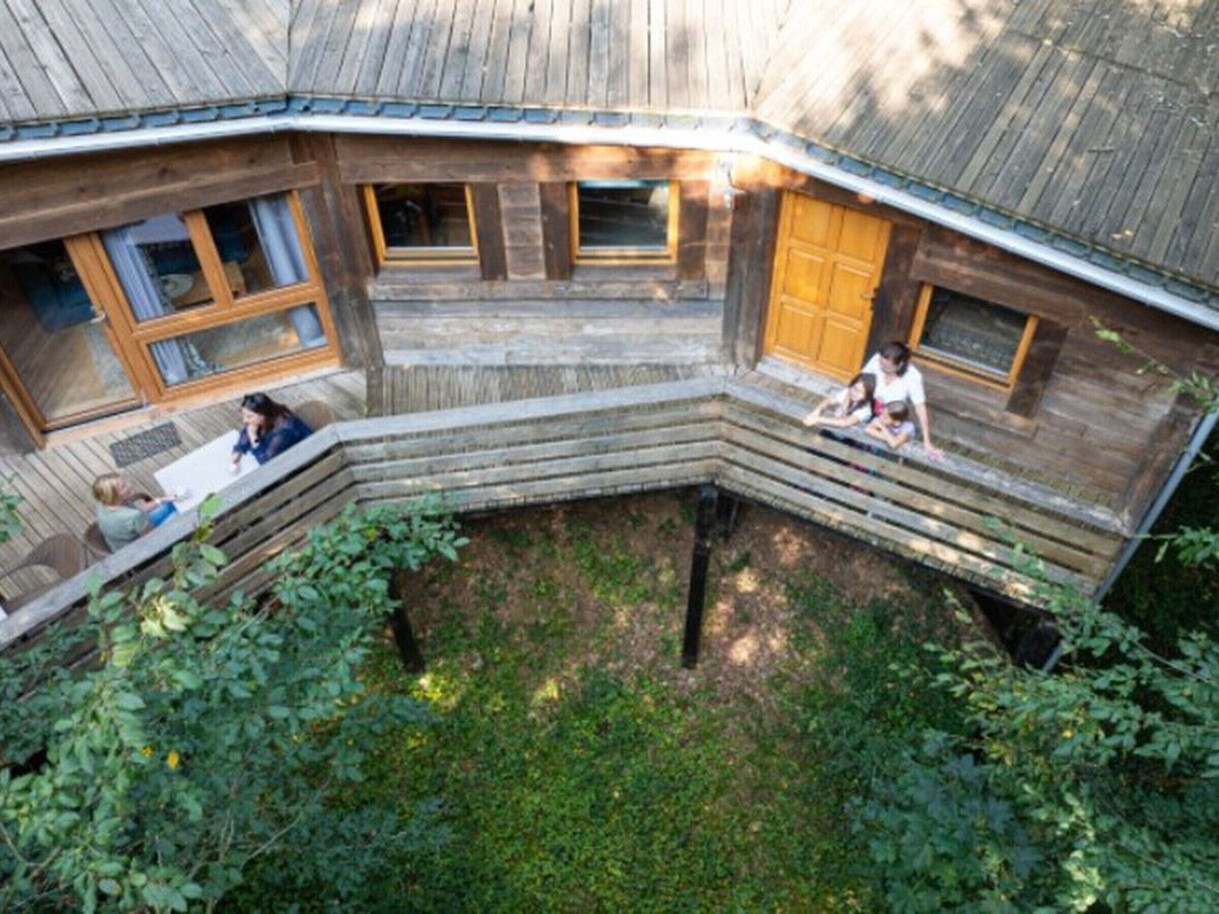 Une cabane en bois dotée d’un toit incurvé, de nombreuses fenêtres et d’un petit porche fermé.