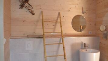 Interior de madera con una escalera, un espejo redondo y un lavamanos.
