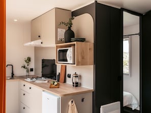 Eine kompakte Küche mit Mikrowelle, kleinem Kühlschrank und einer Holzausziehtafel.